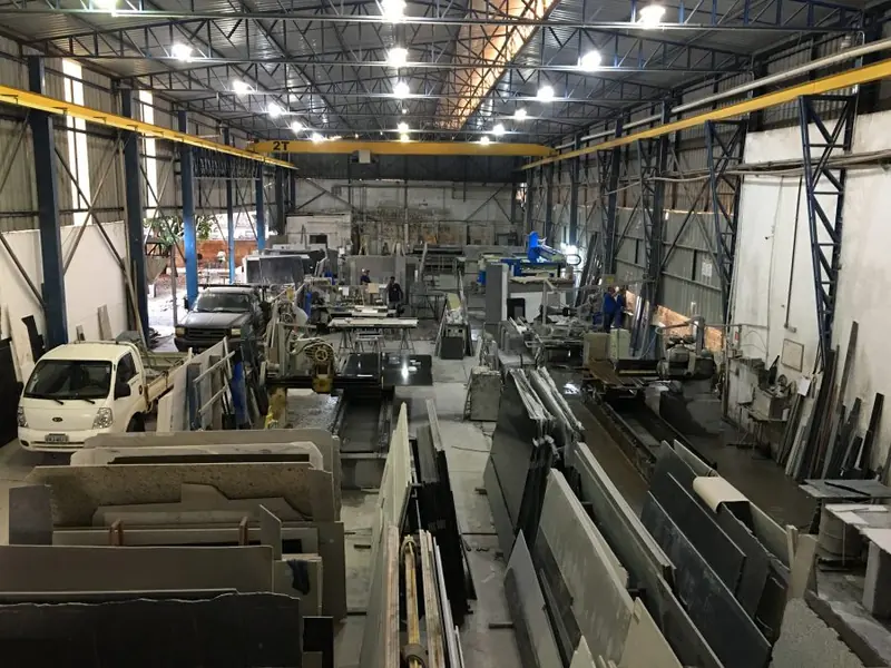 Salão de produção da Marmoraria Farina, com chapas de pedra e pontes rolantes